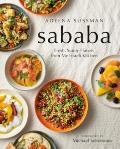 The cover of Sababa cookbook with bright orange, yellow, and red dishes in colorful bowls set on a white cloth.